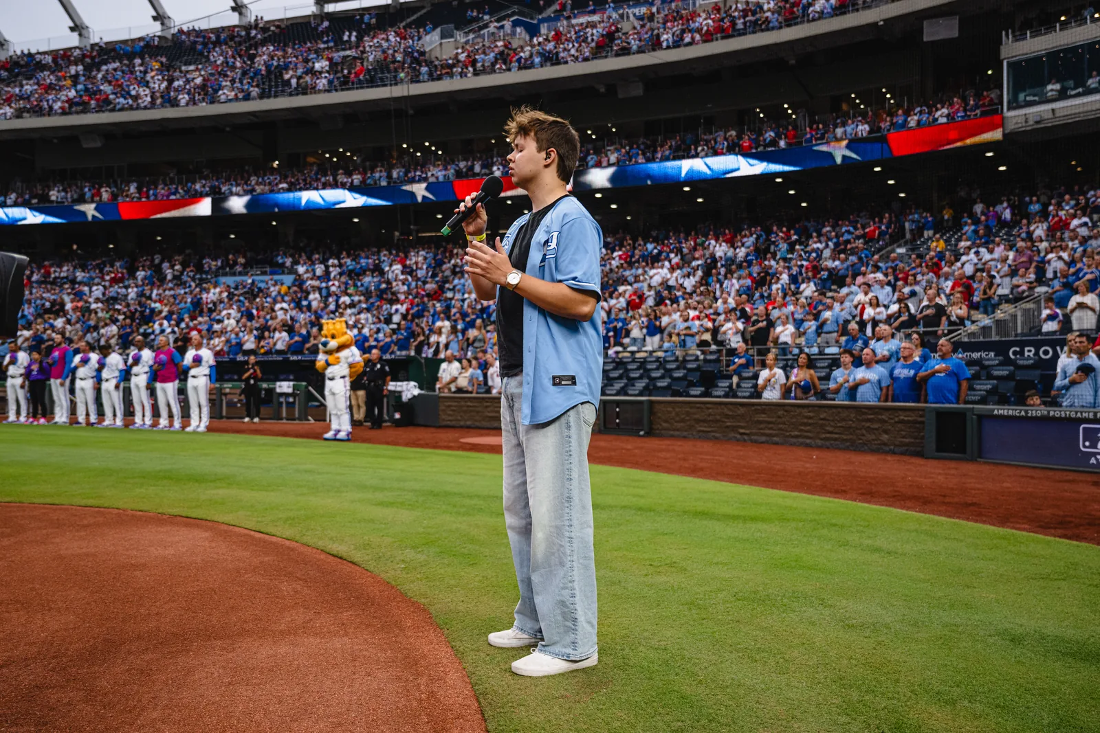 Max Cooper III singing the national anthem on the field at Kauffman Stadium